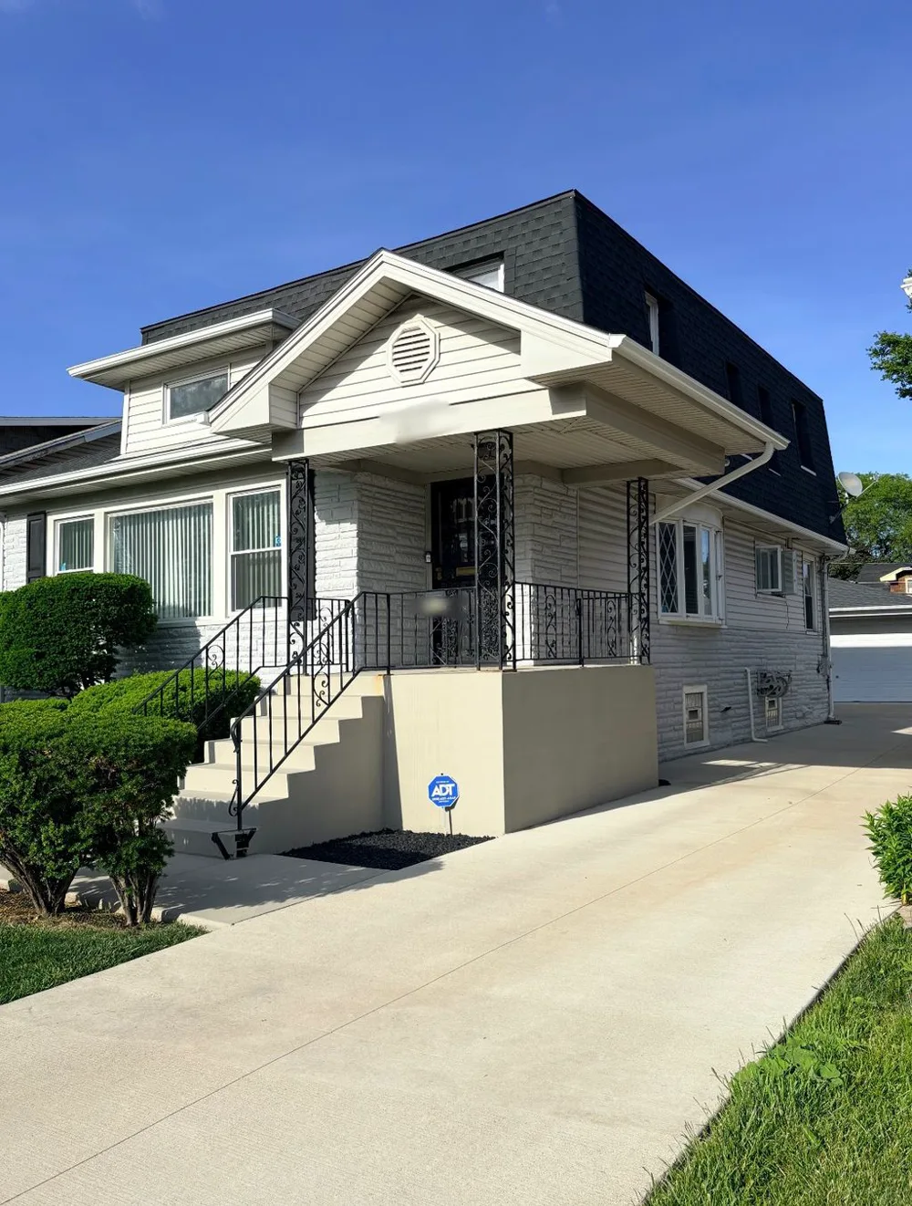 White and gray repainted bungalow exterior under a clear sky